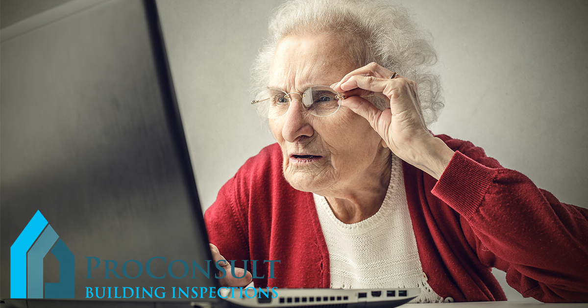 old lady adjusting glasses to read a laptop